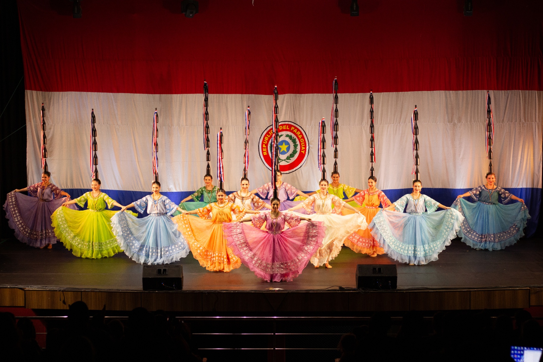 Bailarinas de danza paraguaya de DANZAR con polleras de colores y la bandera nacional